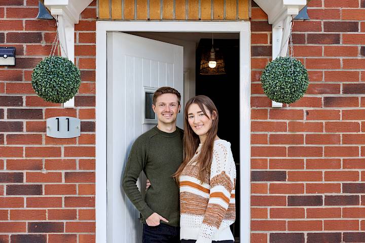 happy couple at front door of new home