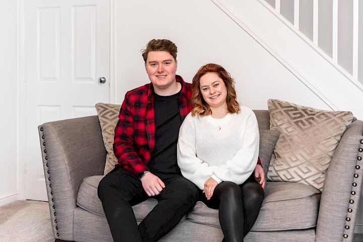 Happy couple sat on love seat.