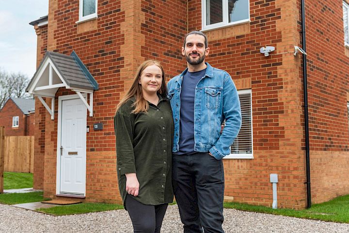 Happy couple standing in front of home.